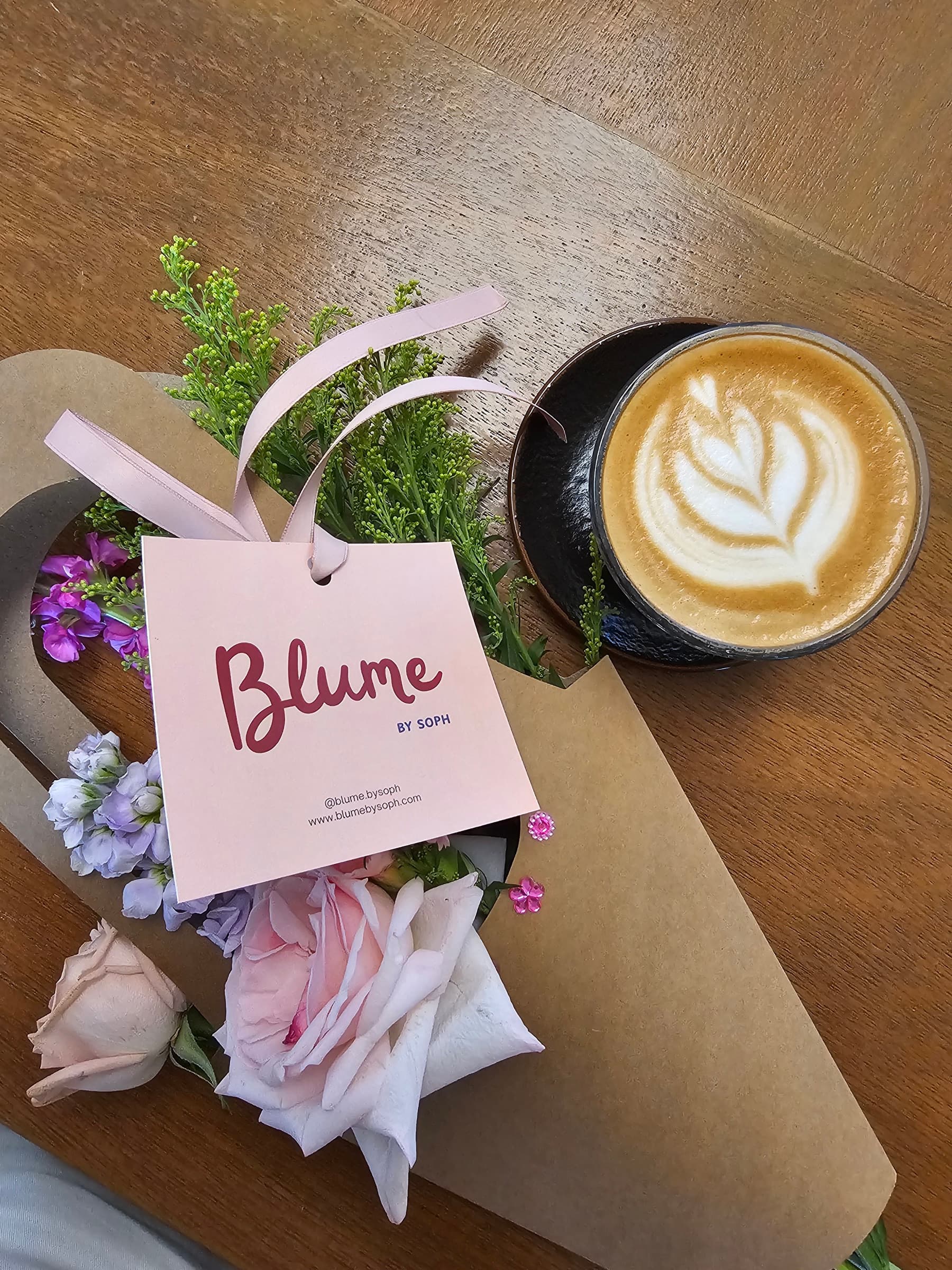 A personal Blume bouquet beside a cup of coffee at KOHA Bistro.