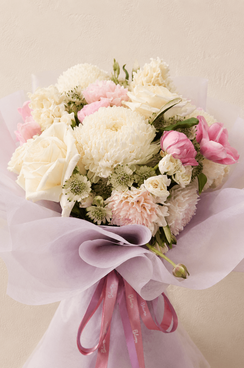 Blush-and-cream bouquet with pink tulips and soft white blooms, wrapped in lilac paper for “To Myself, First”.